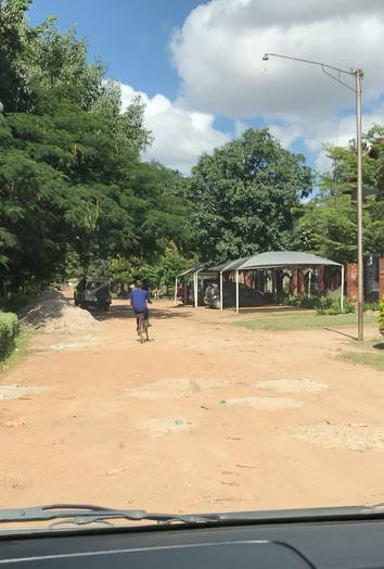 Allmählich nähern uns dem Ziel: Kaum von der Hauptstraße abgebogen zeigt sich das für das Sambia typische Straßenbild, dass unsere Weiterfahrt auf Grund unzähliger Schlaglöcher verlangsamt.